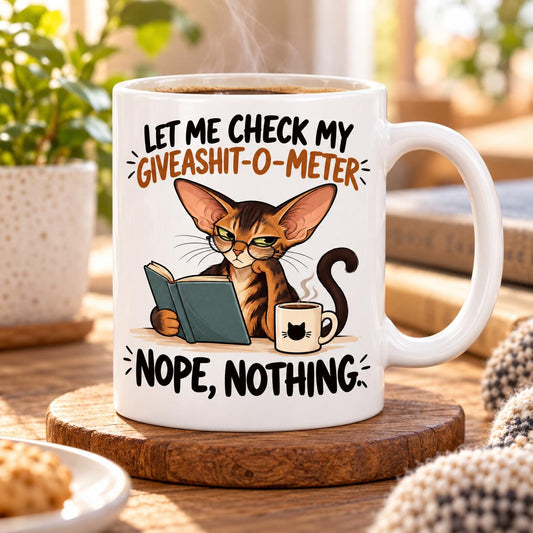 Rendering of white ceramic mug with cartoon thinking orintal cat saying "let mi check my giveashit-o-meter" on wooden table.