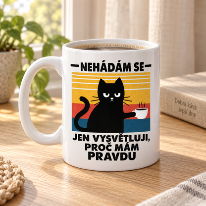 Lifestylová fotografie bílý keramický hrnek s černou kočkou, šálkem kávy a vtipným nápisem Nehádám se, jen vysvětluji, proč mám pravdu.