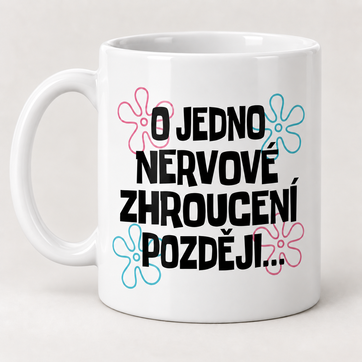 Bílý keramický hrnek s nápisem O jedno nervové zhroucení později a barevnými květinovými prvky.