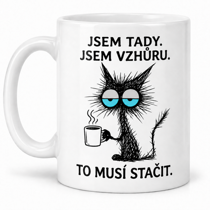 Bílý keramický hrnek s unavenou černou kočkou, hrnkem kávy a vtipným nápisem Jsem tady. Jsem vzhůru. To musí stačit.