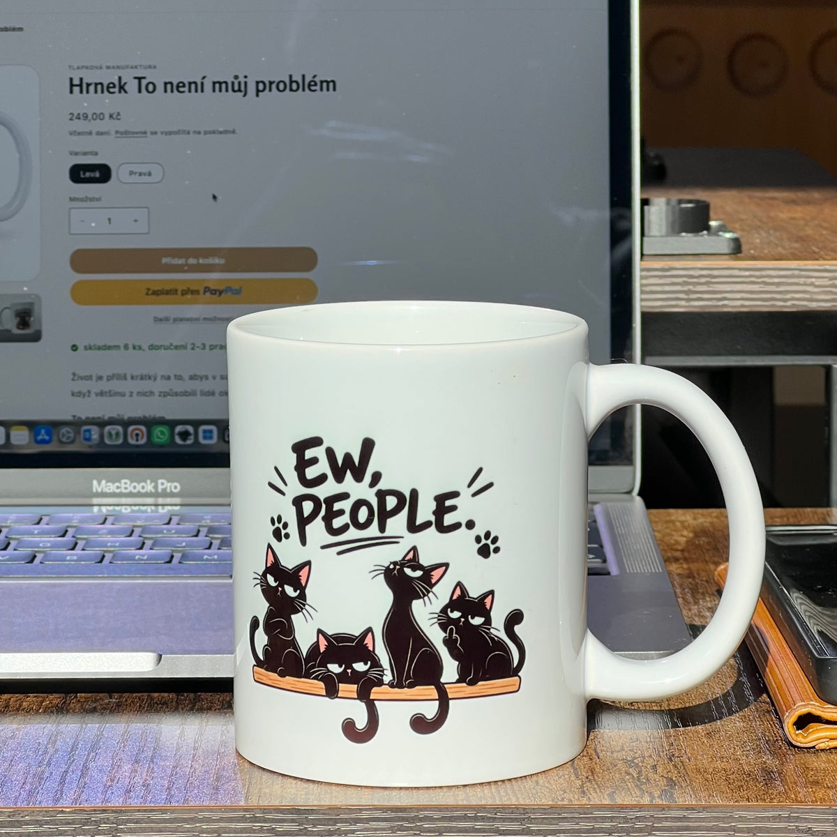 Bílý keramický hrnek s motivem skupiny černých koček a povzdechem "EW, people!" na kancelářském stole