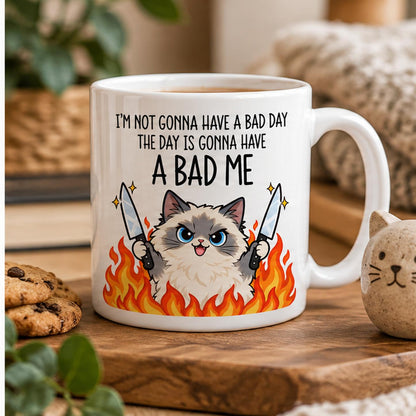 Rendering of white ceramic mug with cartoon pumped ragdoll cat saying "I'm not gonna have a bad day" on wooden table. 