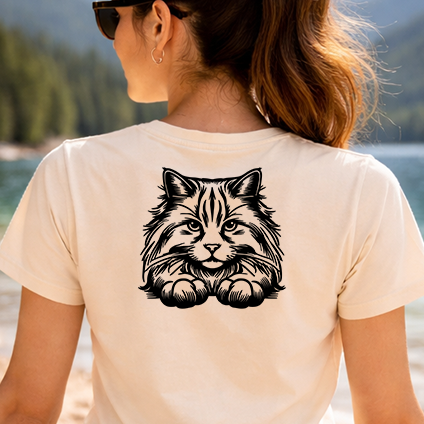 Černobílá stylizovaná nažehlovačka sibiřské kočky vykukující přes hranu s tlapkami aplikovaná na zadní straně pískového trička.